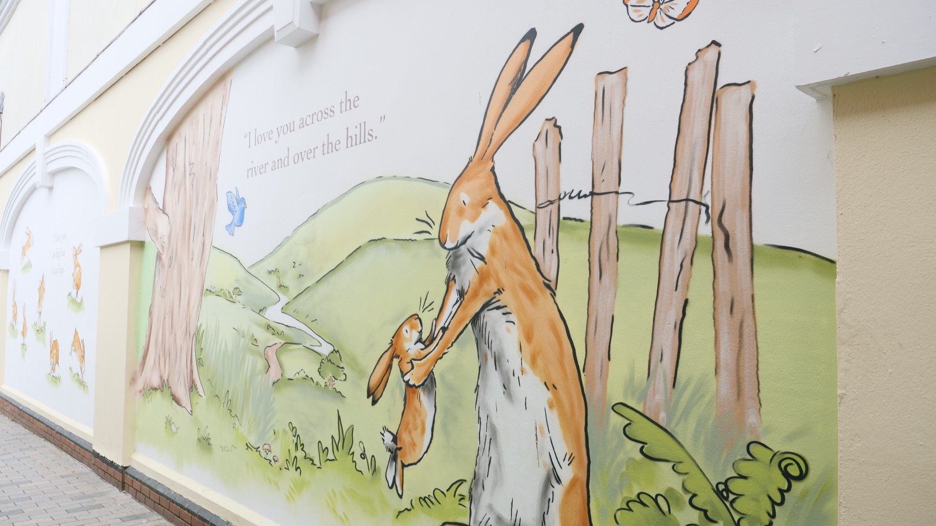 A spray painted Little Nutbrown Hare and Big Nutbrown Hare alongside a quote from the book saying, 'I love you across the river and over the hills'