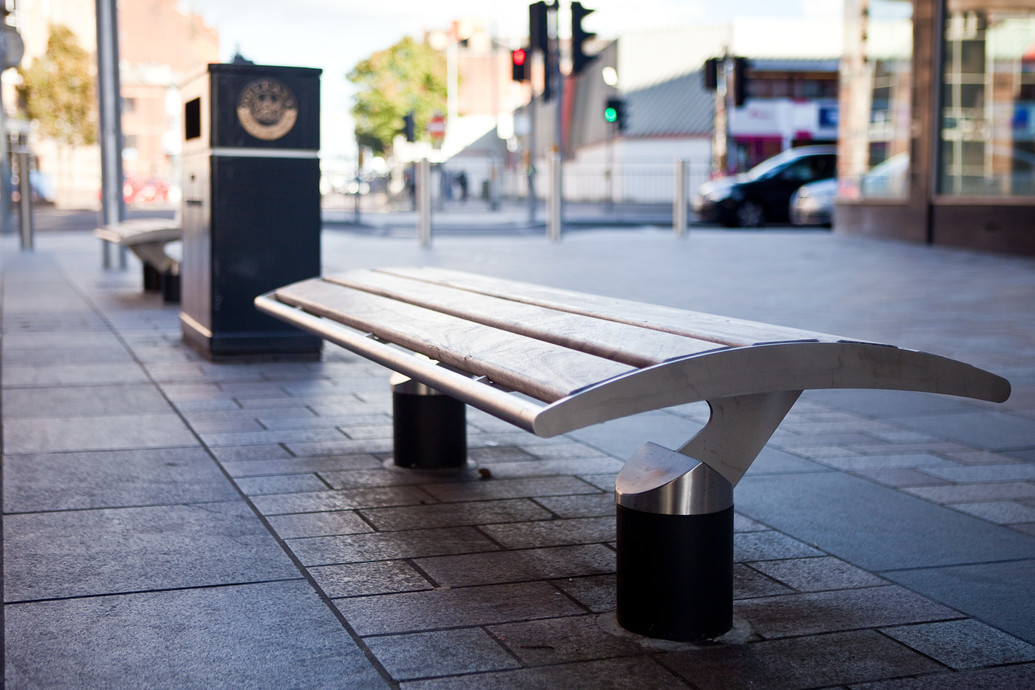 Image illustrating a typical hardwood and steel public seat which has no back or arms